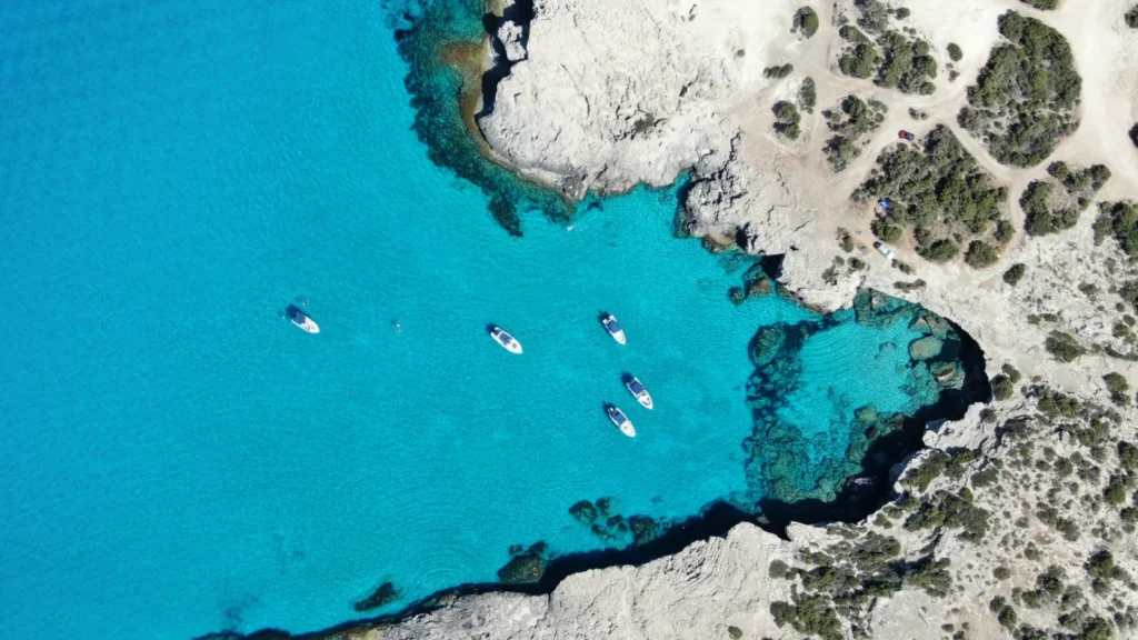 Cala rocosa en Chipre con barcos sobre aguas cristalinas, relacionada con el estilo de vida de residentes fiscales non-dom