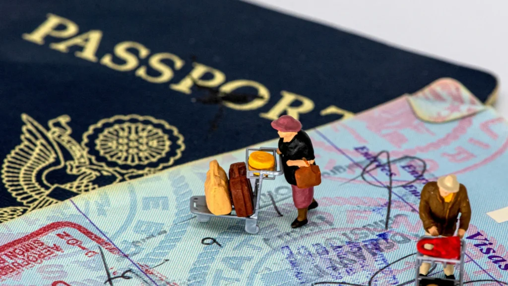 Un primer plano de un pasaporte abierto con sellos de visa y figuras en miniatura de viajeros, simbolizando el proceso de baja de residencia fiscal y mudanza internacional.