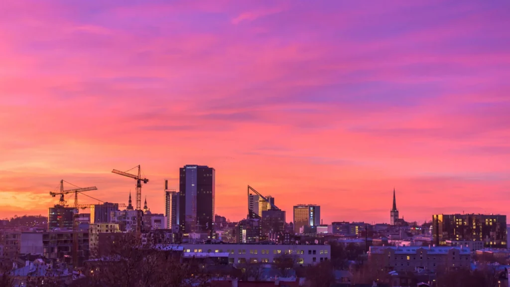 Atardecer con tonos rosas y violetas sobre el skyline moderno de Tallin, reflejando el desarrollo tecnológico de las empresas en Estonia.