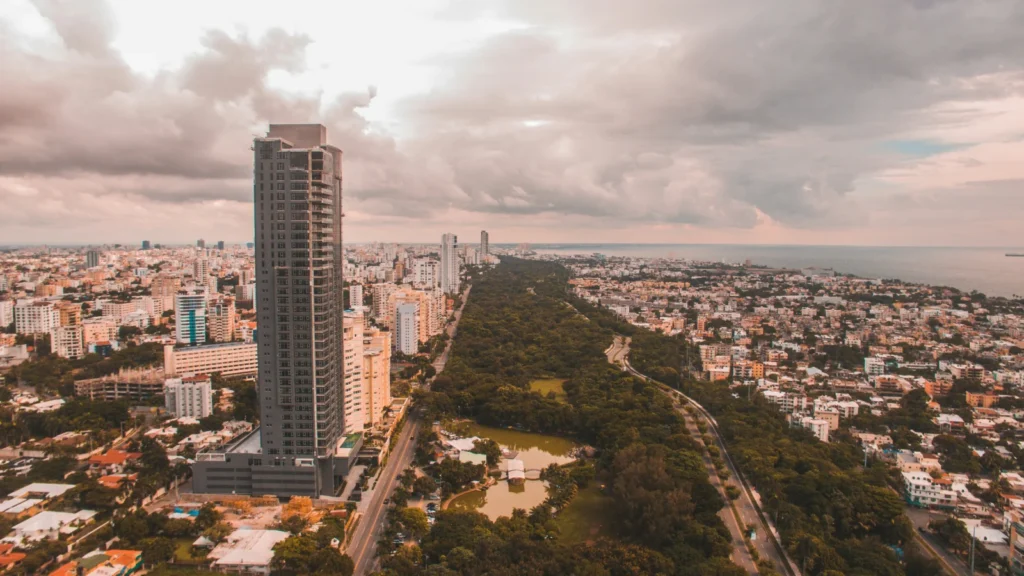 Vista aérea panorámica de la ciudad de Santo Domingo con rascacielos modernos y zonas verdes junto al mar, donde se tramita el permiso de residencia permanente.