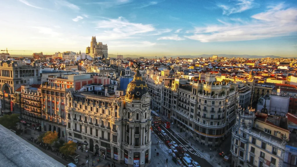 Panorámica aérea del Edificio Metrópolis y las calles del centro de Madrid durante el atardecer, ideal para inversores y profesionales extranjeros en España.