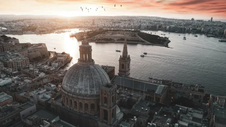 Vista aérea de la Basílica de Nuestra Señora del Monte Carmelo y el puerto de La Valeta al atardecer, representando el entorno del régimen fiscal non-dom en Malta.