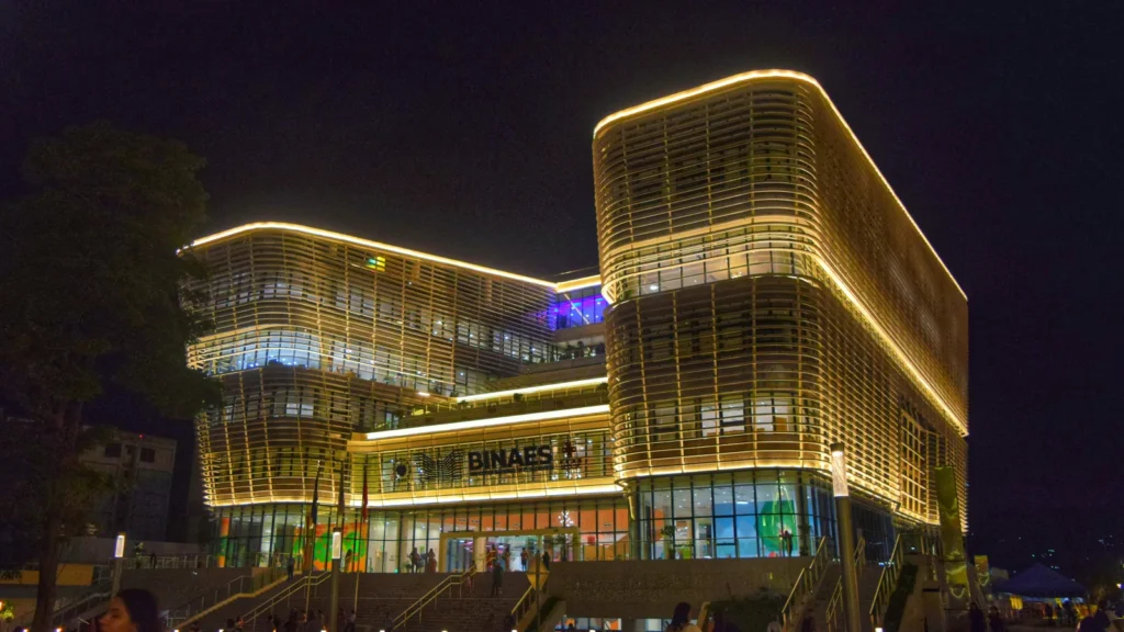Edificio moderno iluminado de noche de la Biblioteca Nacional de El Salvador (BINAES) en San Salvador.
