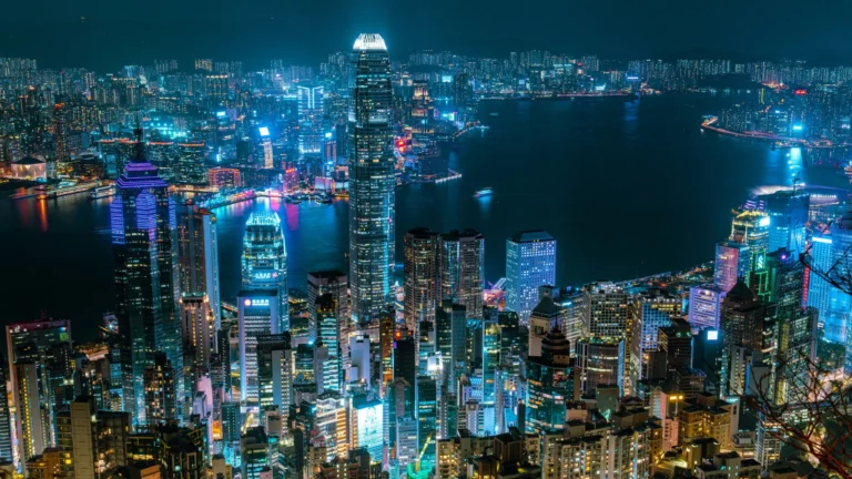 Vista nocturna iluminada del centro financiero y los distritos de negocios de Hong Kong junto al mar.