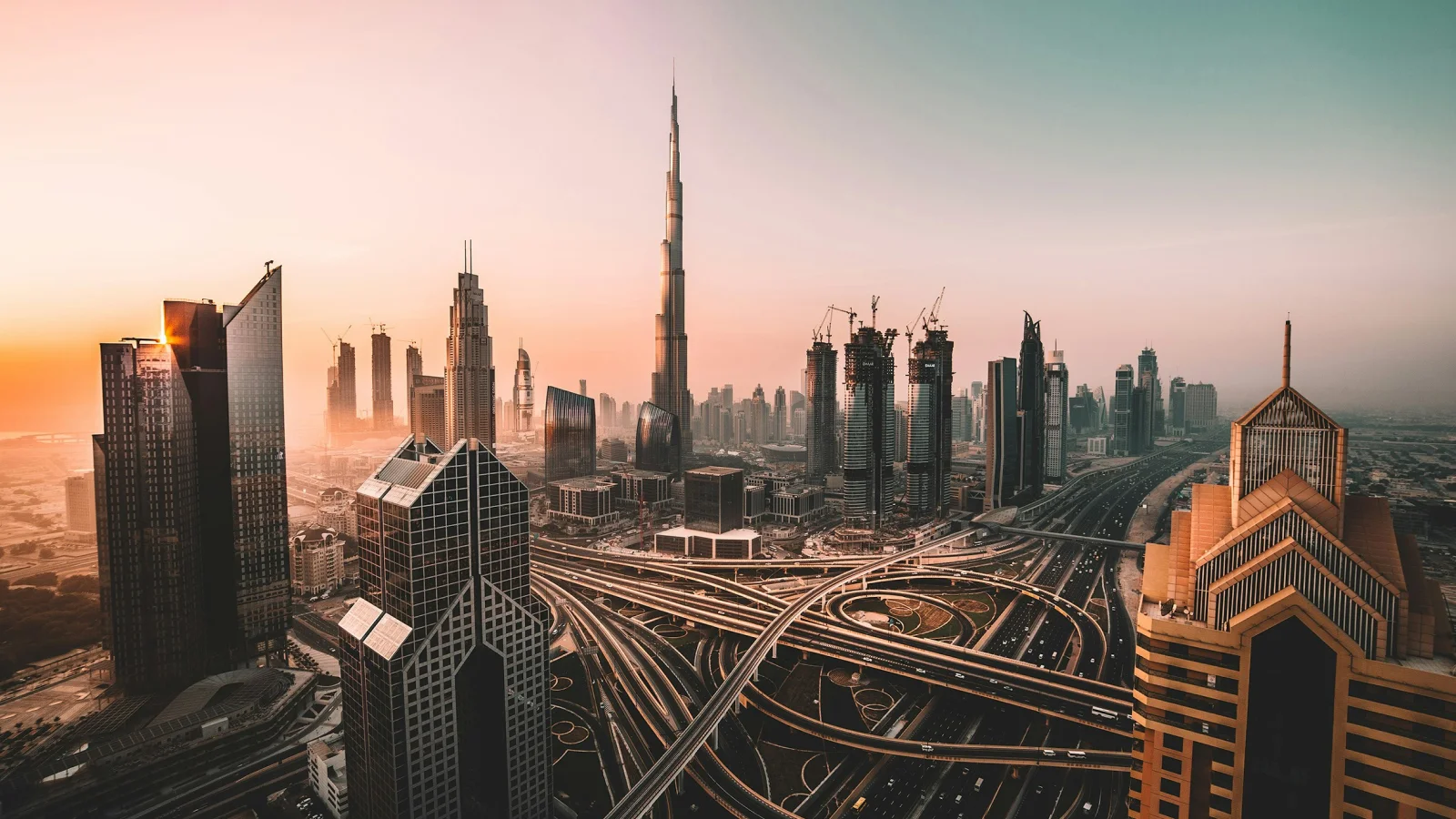 Vista panorámica del skyline de Dubái al atardecer con el rascacielos Burj Khalifa y la infraestructura de autopistas.