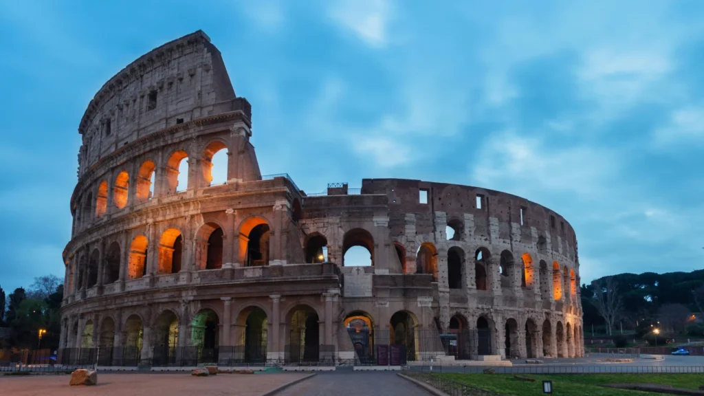 El Coliseo Romano iluminado al anochecer, símbolo de la cultura e historia para quienes buscan la Golden Visa en Italia.