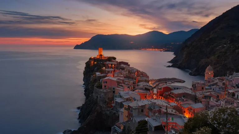 Vista panorámica del pueblo costero de Vernazza en Cinque Terre iluminado durante el atardecer mediterráneo.