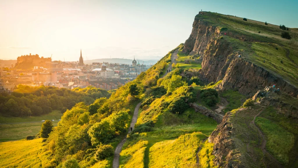 Colinas verdes y senderos naturales iluminados por el atardecer con una ciudad británica al fondo, ilustrando la calidad de vida para expatriados.