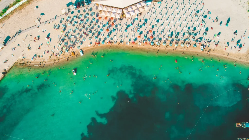 Vista aérea de una playa sombreada junto a aguas turquesas en el Mar Negro, ilustrando el estilo de vida para nómadas digitales en Bulgaria.