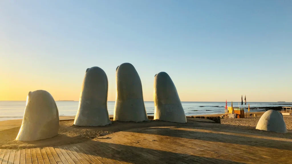 Playa mansa de Punta del Este con edificios residenciales al fondo durante el atardecer, ideal para nómadas fiscales y emprendedores.