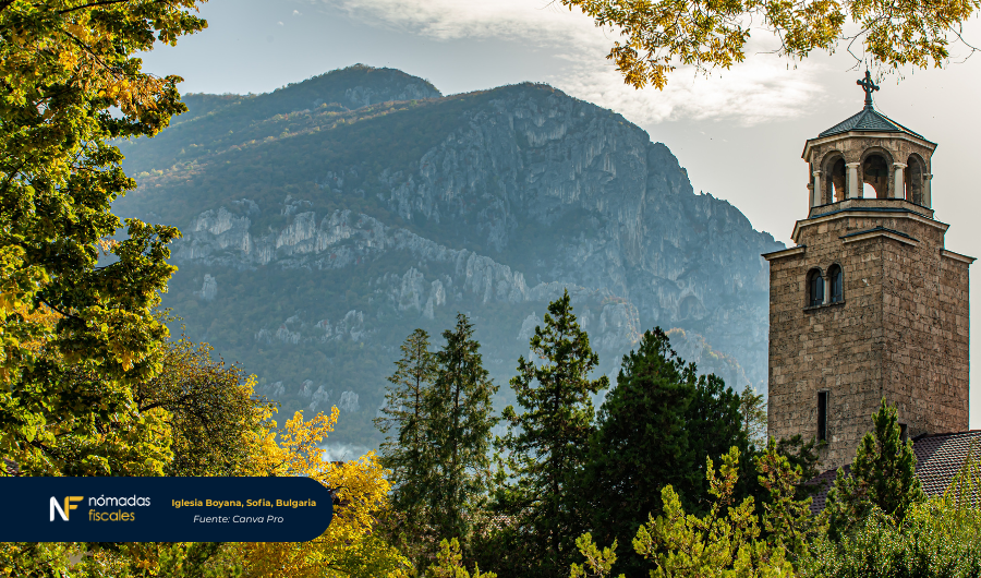 Iglesia Boyana en Sofía, Bulgaria, rodeada de árboles y montañas al fondo.