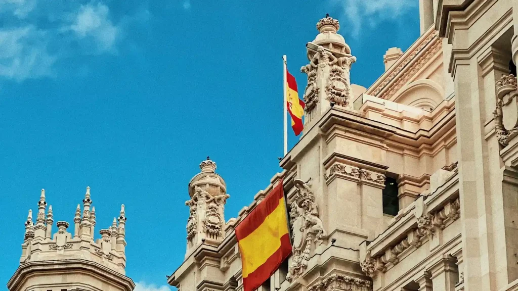 Fachada histórica en España con banderas visibles, imagen asociada a fiscalidad y residencia internacional.