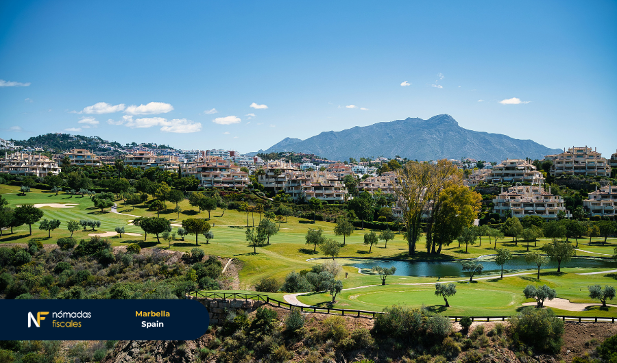 Panoramic view of a golf course in Marbella, Spain, with residential buildings and mountains in the background