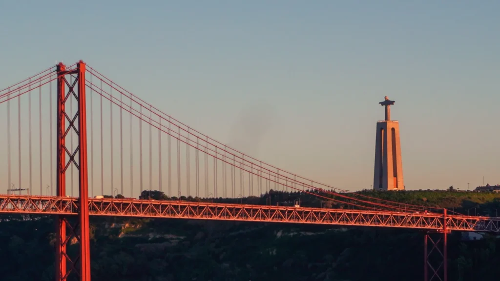 Vista del puente y monumento de Cristo Rey en Portugal durante el atardecer, imagen relacionada con movilidad internacional y fiscalidad.